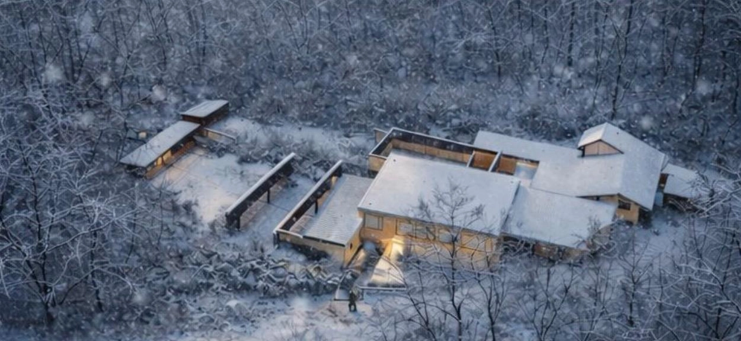 Schützenverein Bissingen/Enz e.V. – Eine Luftaufnahme von modernen, schneebedeckten Häusern, die in einem stillen, verschneiten Wald warm leuchten.