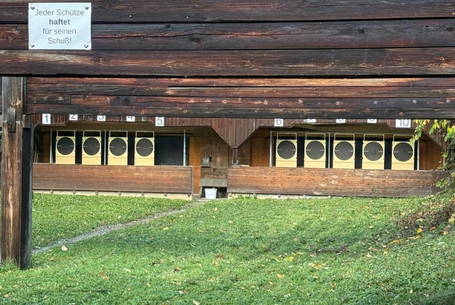 Schützenverein Bissingen/Enz e.V. – Ein Freiluft-Schießstand mit Holzunterständen, einer Rasenfläche davor und Papierzielscheiben, die über mehrere Bahnen verteilt aufgestellt sind.