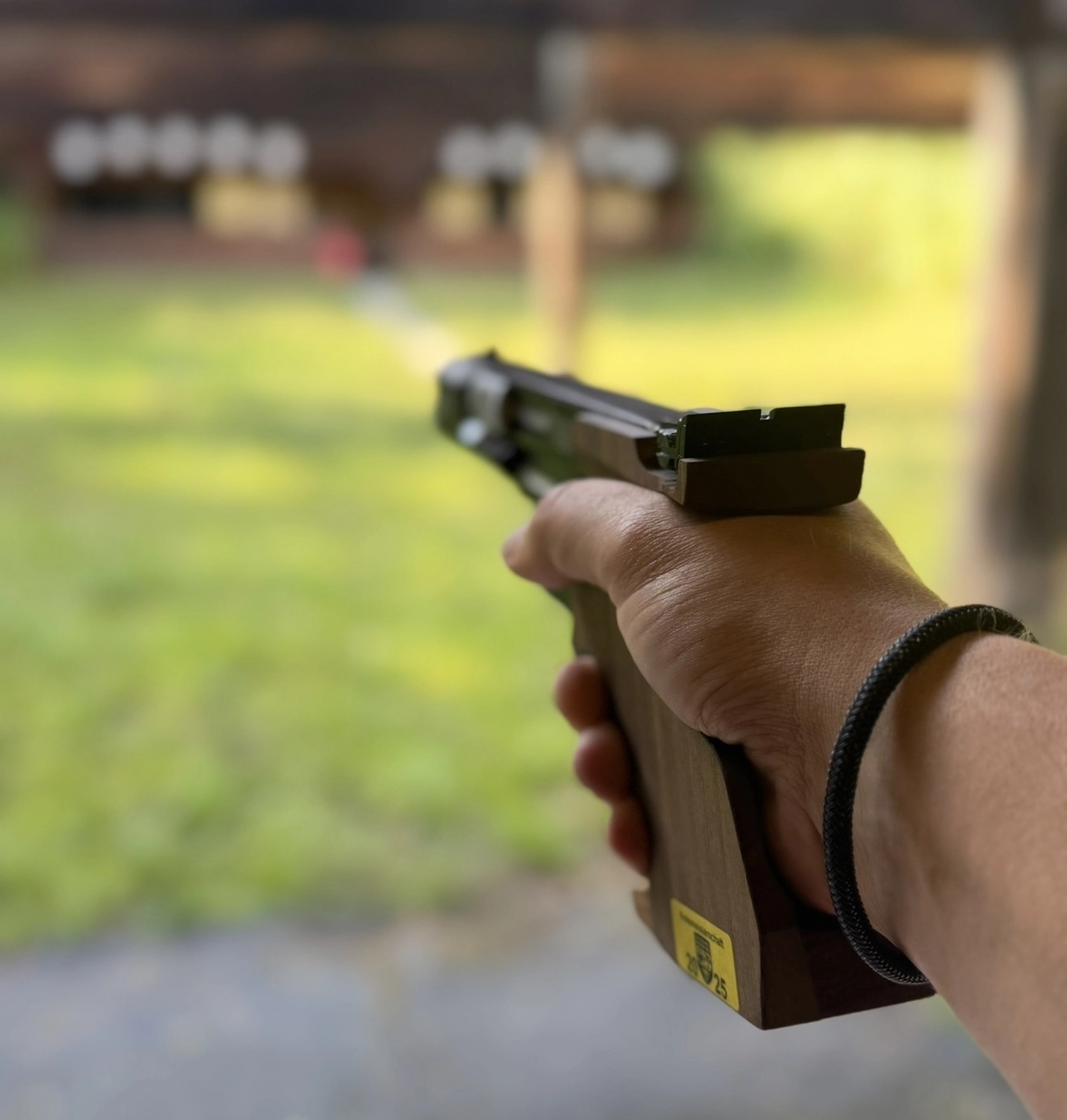 Schützenverein Bissingen/Enz e.V. – Blick über die Schulter auf eine Hand, die auf einem verschneiten Schießstand im Freien mit einer Pistole zielt.