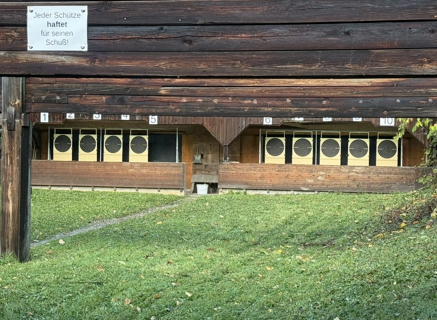 Schützenverein Bissingen/Enz e.V. – Ein Freiluft-Schießstand mit Holzunterständen, einer Rasenfläche davor und Papierscheiben, die auf mehreren Bahnen aufgestellt sind.