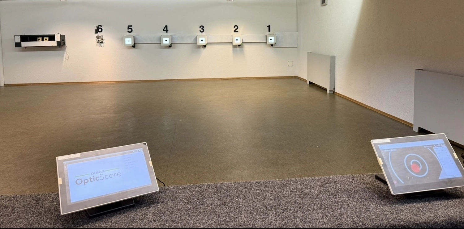 Schützenverein Bissingen/Enz e.V. – Eine Indoor-Schießanlage mit nummerierten Bahnen, elektronischen Zielscheiben an der Wand und zwei Anzeigetafeln im Vordergrund.